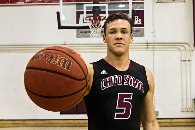 -	Robert Duncan holds a basketball in his Chico State uniform