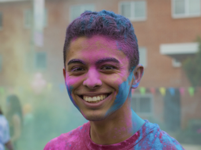 A smiling person covered in colored powder.