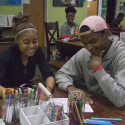 Two students of the Cross Cultural Leadership Center are sitting at a table together drawing a picture.